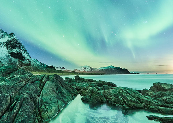 Grüne Naturaufnahme vom Meer, am Himmel ist ein Naturspektakel von Nordlichtern zu sehen
