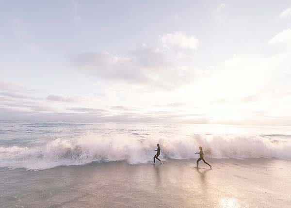 Zwei Personen laufen bei sonnigen Stunden durch das Meer